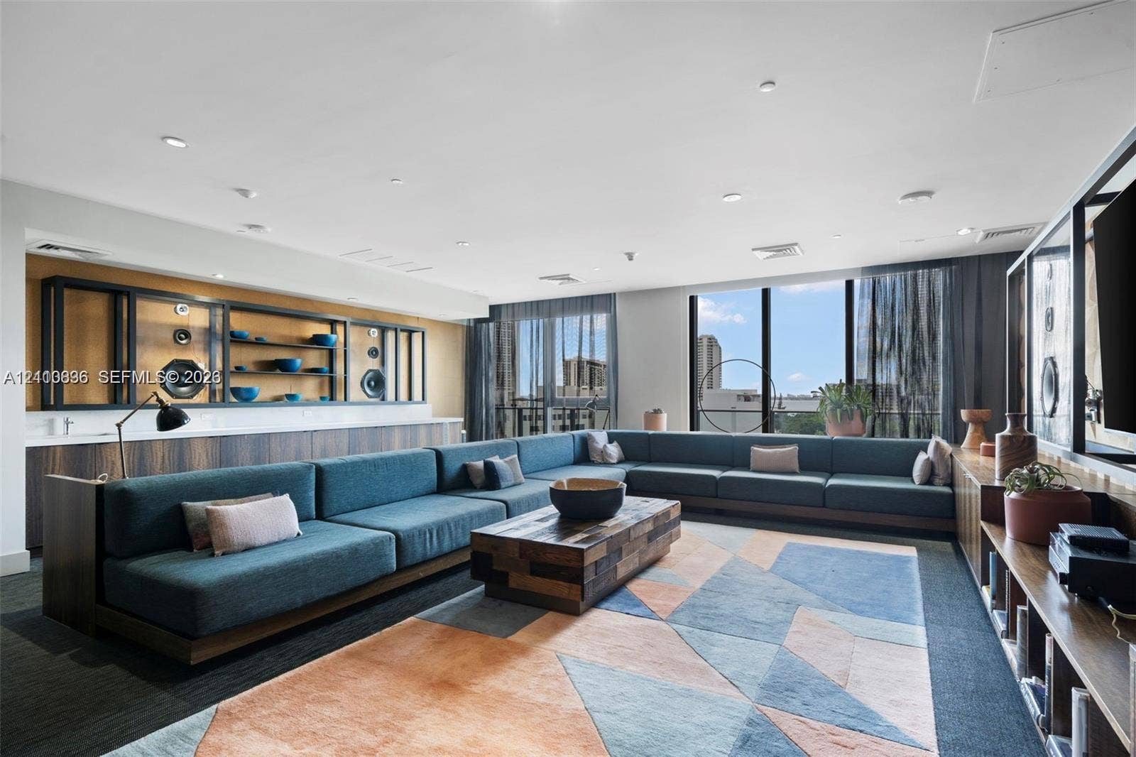 Expansive room featuring floor-to-ceiling windows, custom built-in dark wood cabinetry, recessed lighting, and integrated shelving units