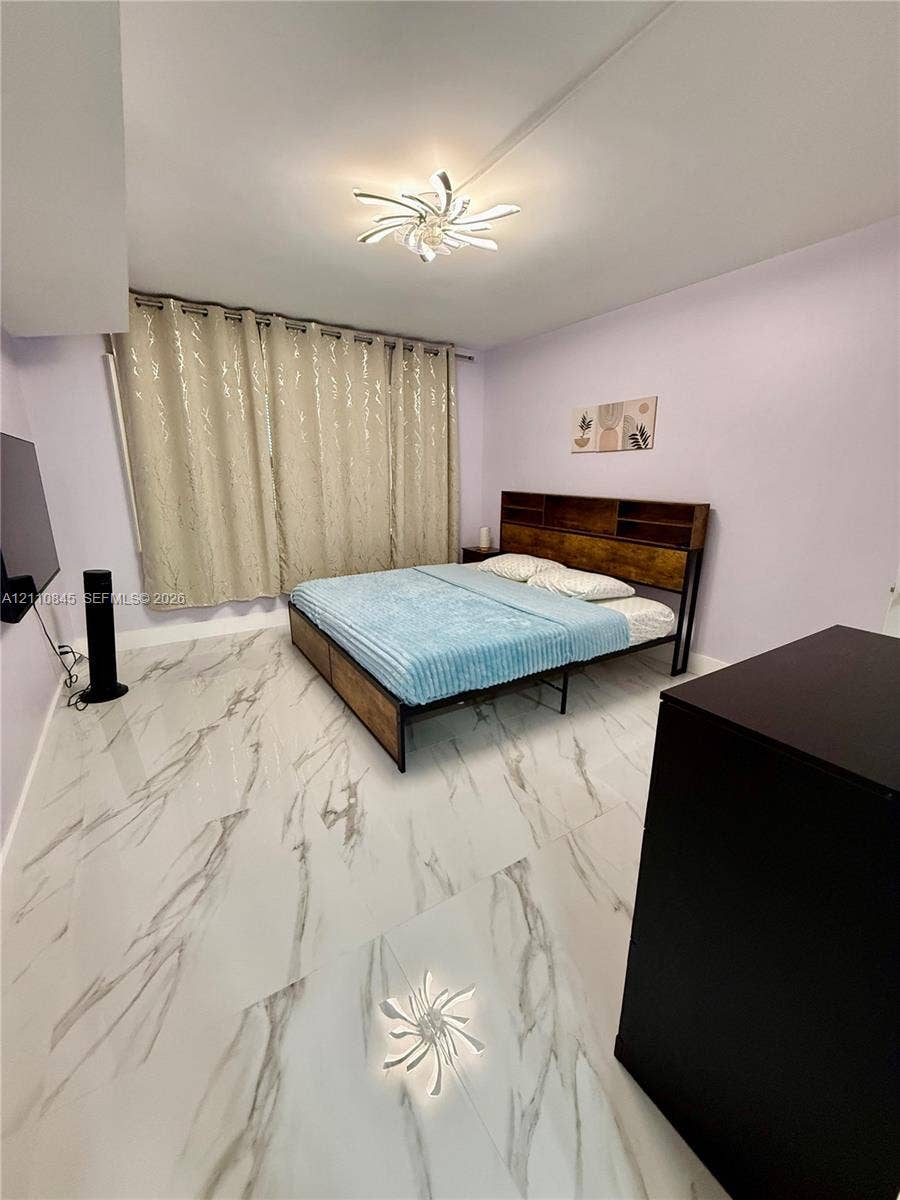 565 Oaks Lane, #410, Pompano Beach, FL 33069 Large-format white tile flooring with grey veining, integrated ceiling-mounted decorative light fixture, and window spanning the length of the wall