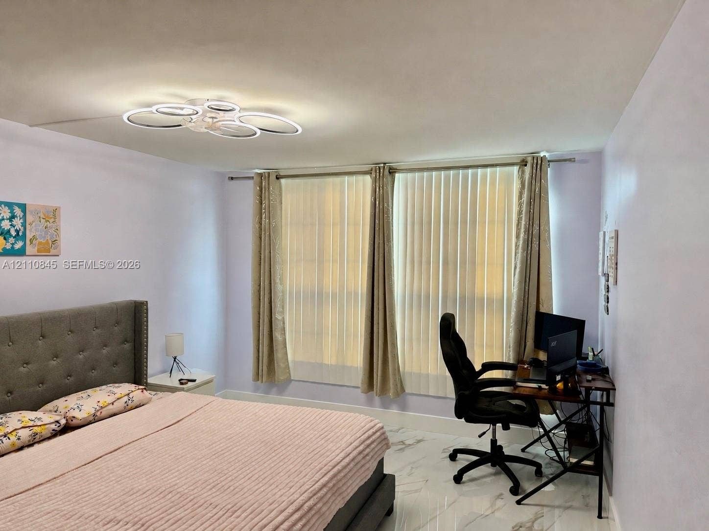 565 Oaks Lane, #410, Pompano Beach, FL 33069 Interior space featuring polished white tile flooring with grey veining, a modern multi-ring LED flush-mount light fixture, and floor-to-ceiling vertical blinds