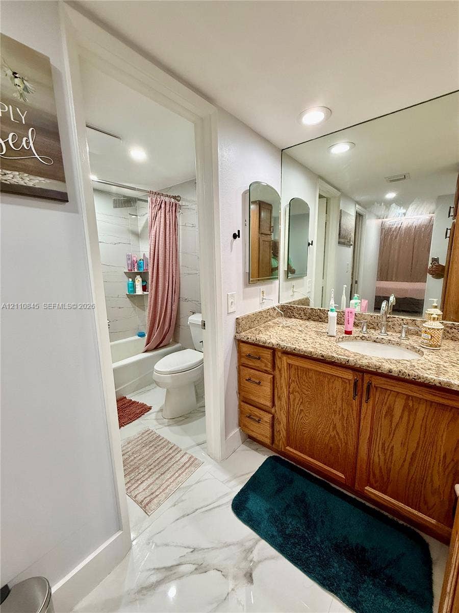 565 Oaks Lane, #410, Pompano Beach, FL 33069 Vanity with stone countertop, wood-finish cabinetry, full-width mirror, recessed lighting, and tile flooring