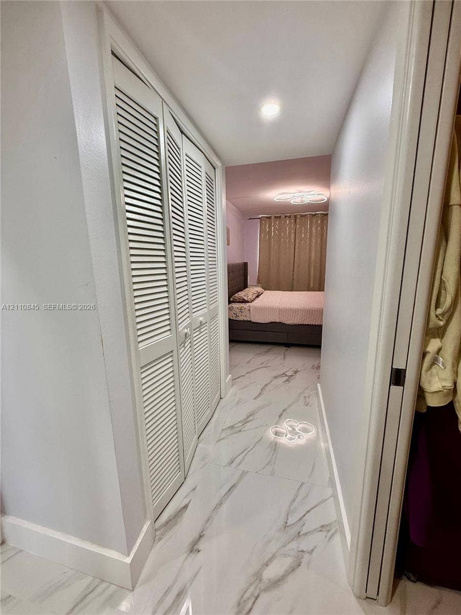 565 Oaks Lane, #410, Pompano Beach, FL 33069 Hallway featuring large-format tile flooring with a neutral-toned pattern, recessed ceiling lighting, and floor-to-ceiling louvered closet doors