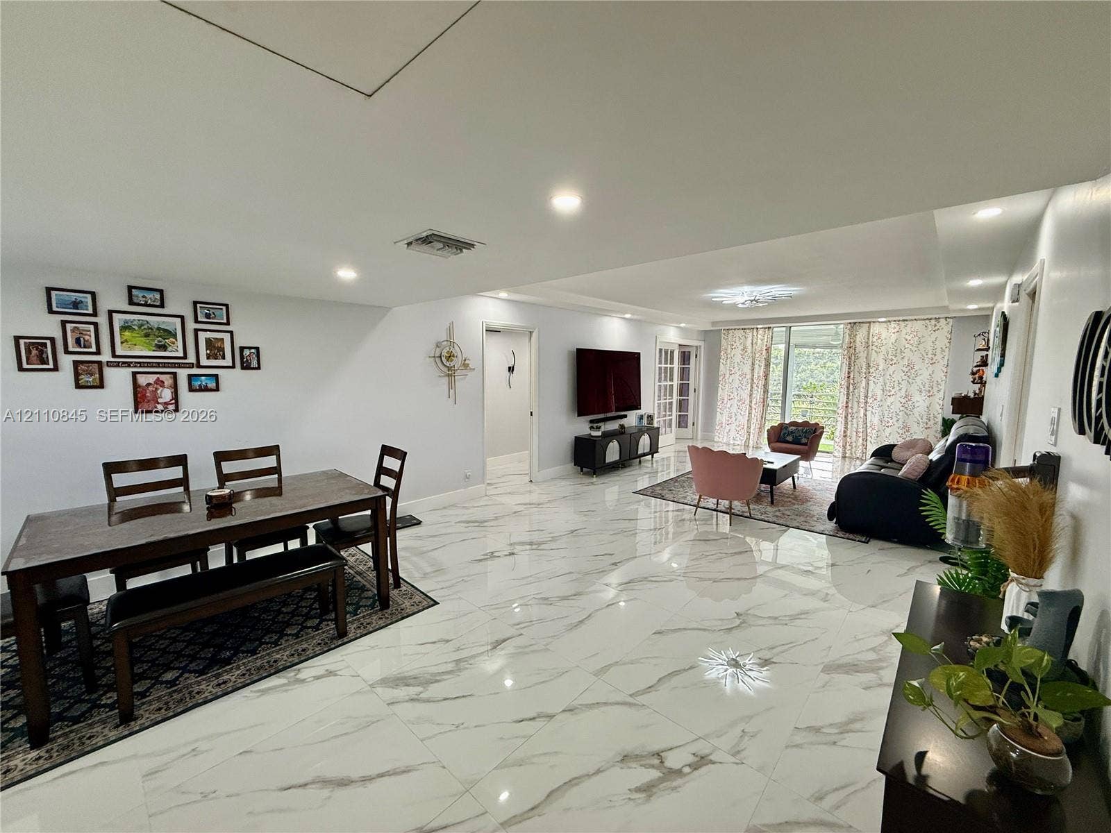 565 Oaks Lane, #410, Pompano Beach, FL 33069 Open-concept interior featuring large-format polished stone-finish flooring, recessed lighting, and expansive glass pane doors leading to exterior space