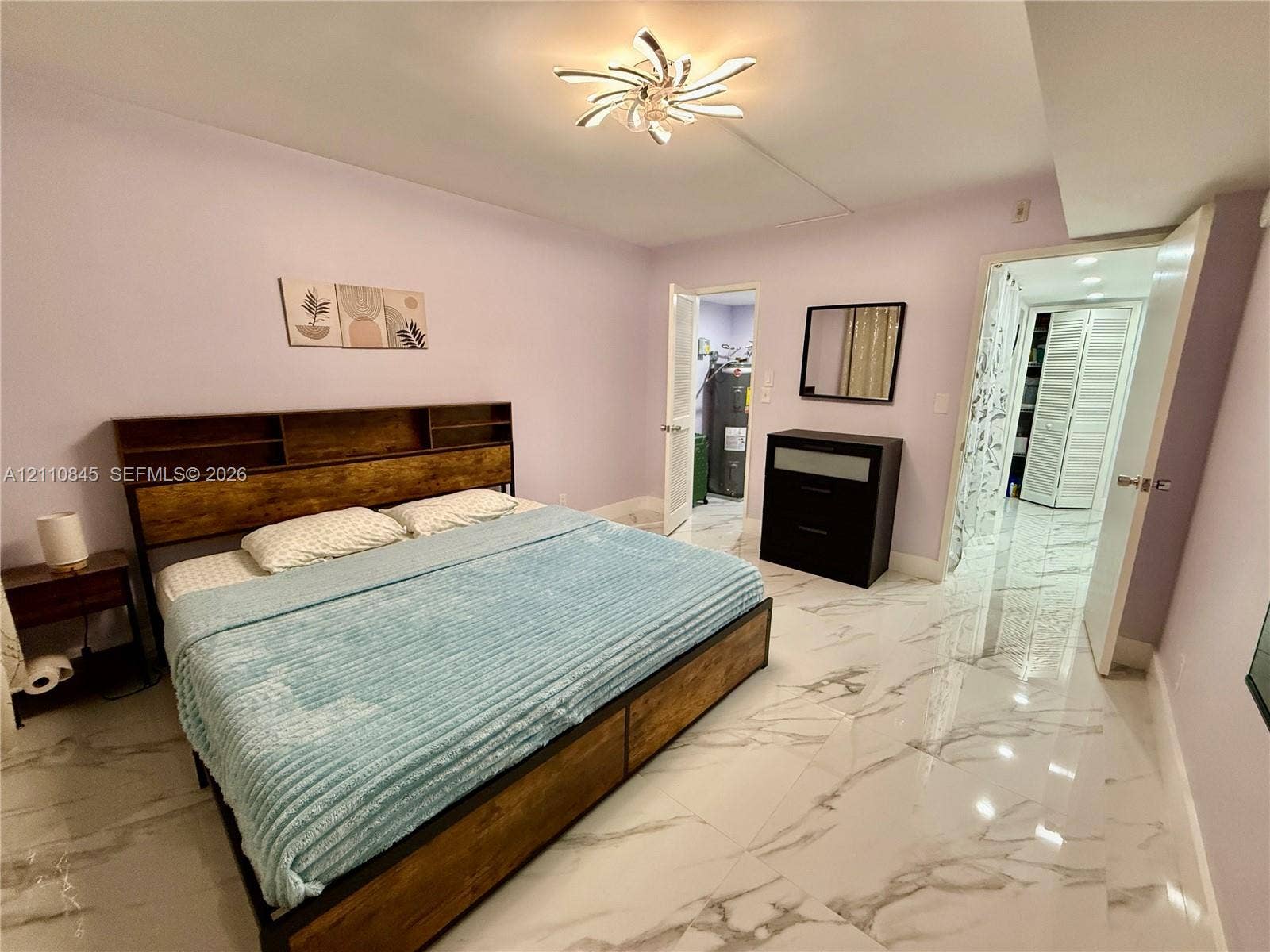 565 Oaks Lane, #410, Pompano Beach, FL 33069 Polished large-format tile flooring with marble-pattern veining, contemporary multi-blade ceiling fixture, and louvered bifold closet doors