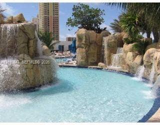 18001 Collins Avenue, #1210, Sunny Isles Beach, FL 33160 Swimming pool featuring naturalistic rock formations, multiple integrated waterfalls, and tropical landscaping