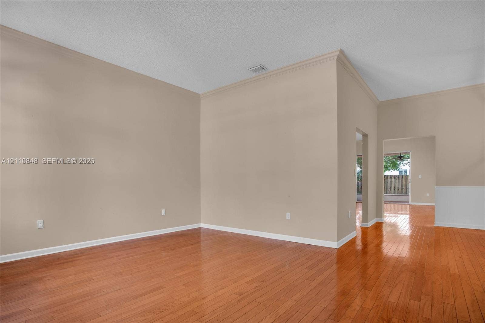 High ceilings featuring crown molding, neutral wall finishes, and polished wood-finish flooring