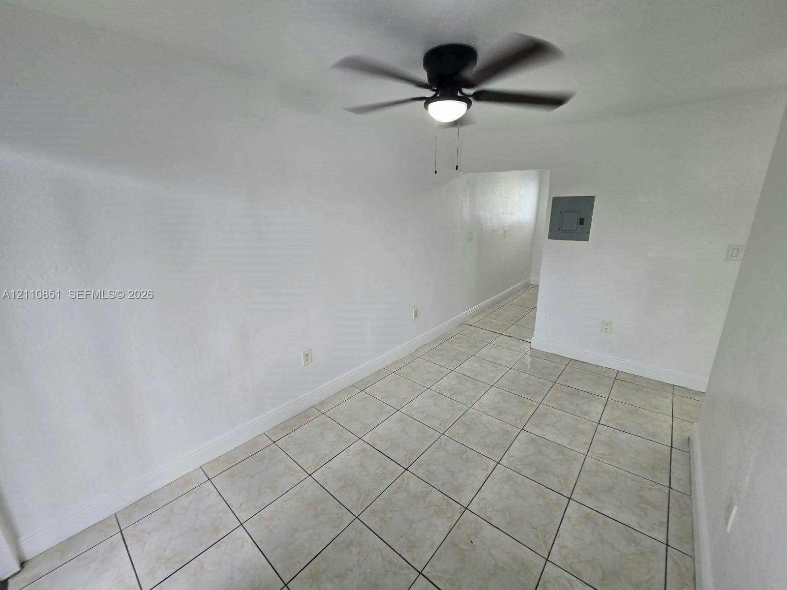 Neutral wall finishes, large-format tile flooring, and a matte black ceiling fan with integrated lighting