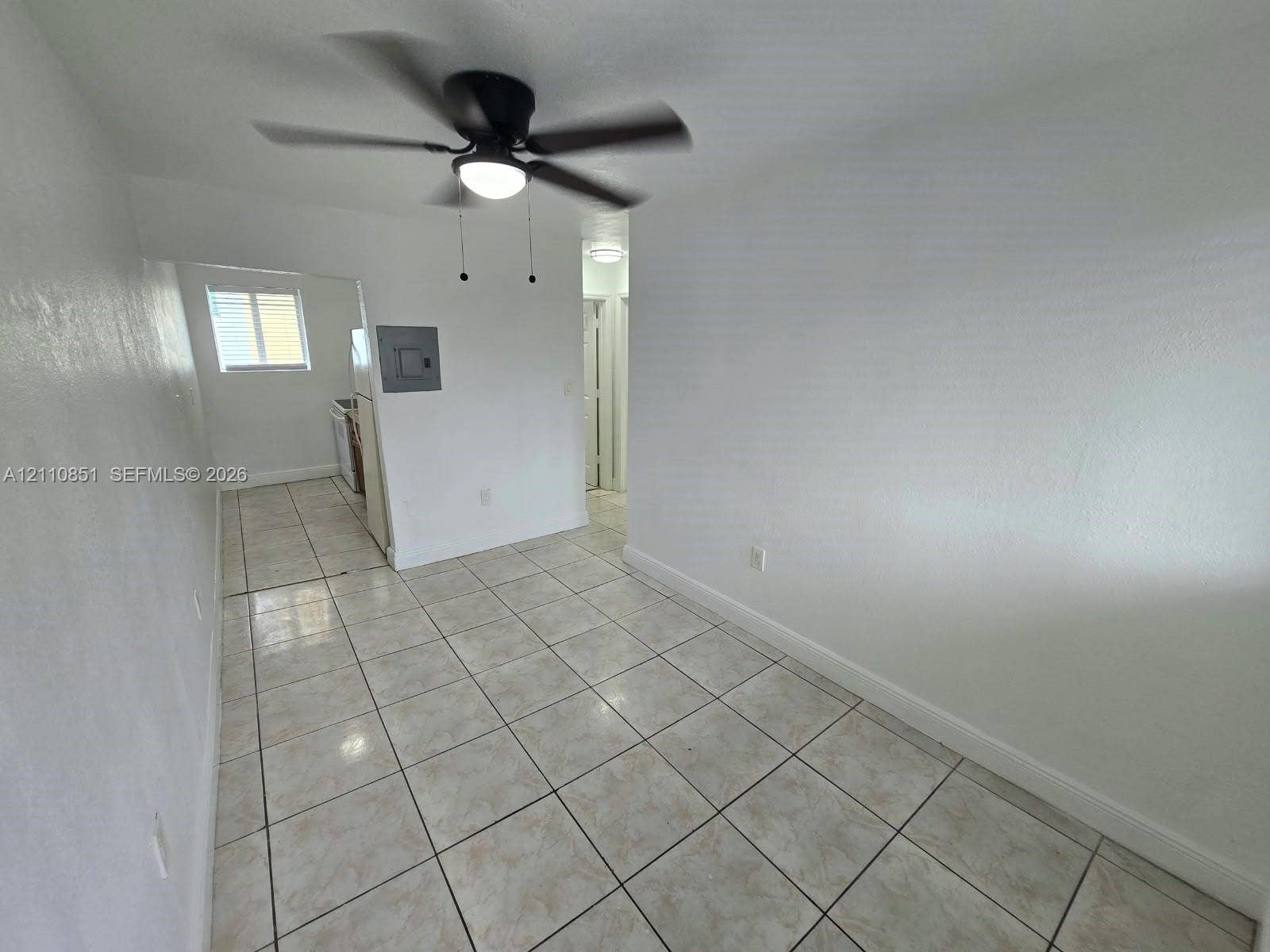 Neutral-toned ceramic tile flooring, matte black ceiling fan, and crisp white wall finishes