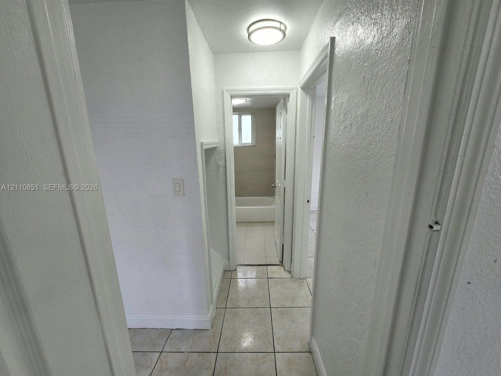 Hallway featuring neutral tile flooring, smooth-finish walls, and a recessed wall niche