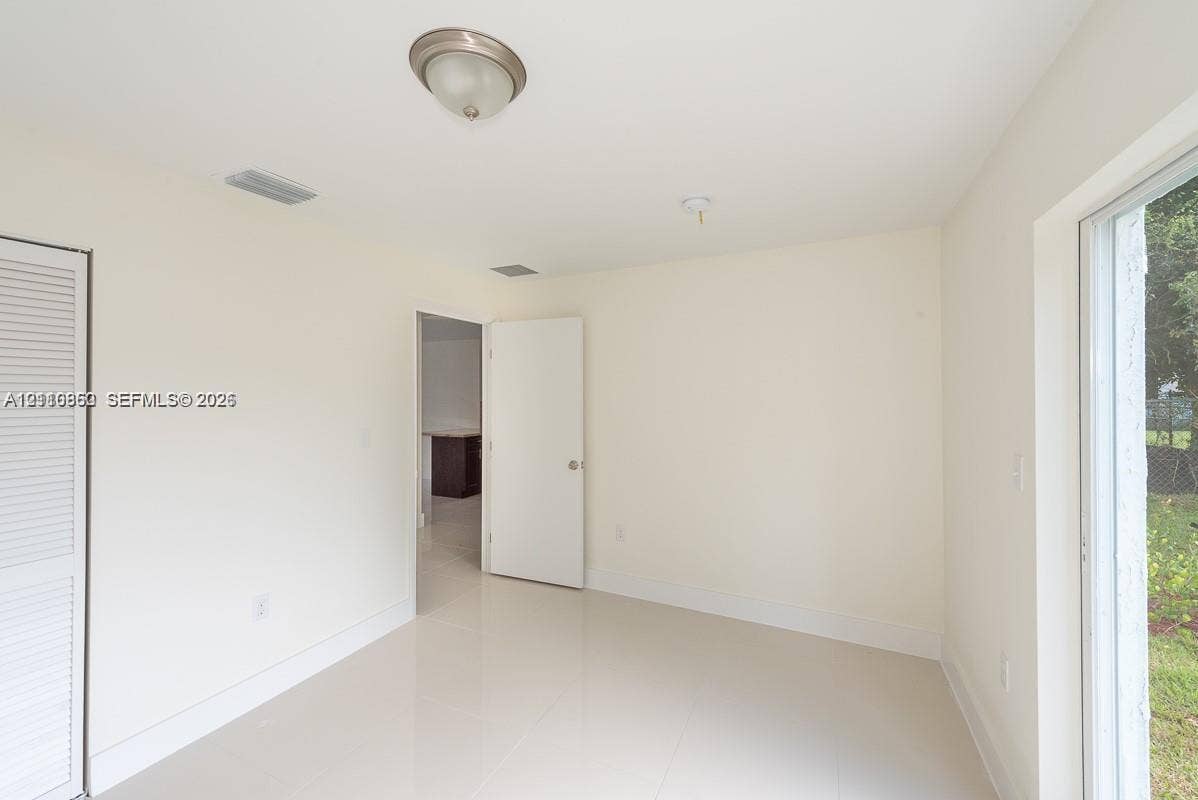 1530 NW 60th Street, Miami, FL 33142 Neutral-toned interior featuring large-format tile flooring, a sliding glass door, and a louvered bi-fold closet door