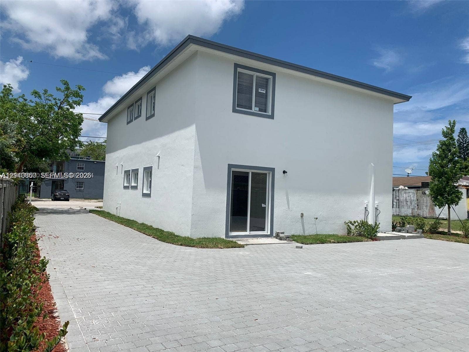 1530 NW 60th Street, Miami, FL 33142 Two-story structure with a smooth stucco exterior, sliding glass door, and a sprawling paved driveway