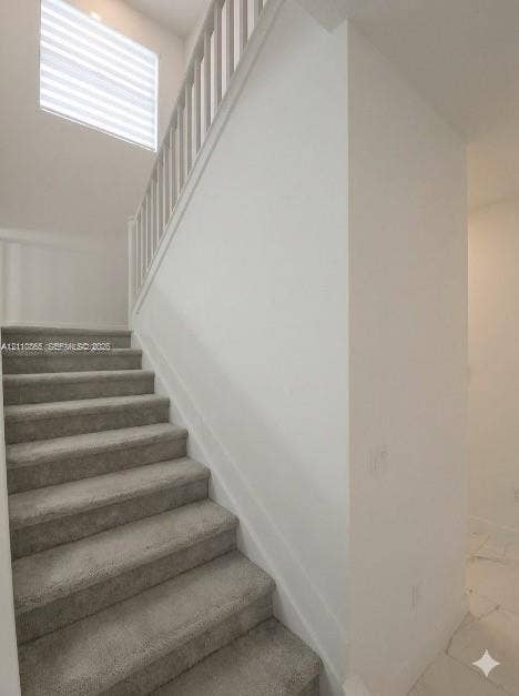 17552 SW 46th Street, Miramar, Miramar, FL 33029 Staircase featuring neutral carpeting, white vertical balusters, and a high-reaching window with integrated blinds