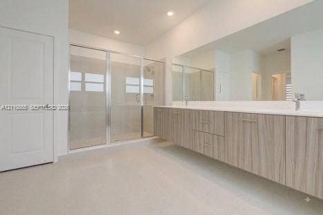 17552 SW 46th Street, Miramar, Miramar, FL 33029 Floating dual-sink vanity with wood-grain cabinetry, expansive wall-to-wall mirror, and glass-enclosed shower with tiled surround