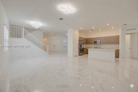 17552 SW 46th Street, Miramar, Miramar, FL 33029 Open-concept interior featuring large-format polished stone flooring, custom wood-finish cabinetry, a central kitchen island, recessed ceiling lighting, and contemporary chandelier fixtures