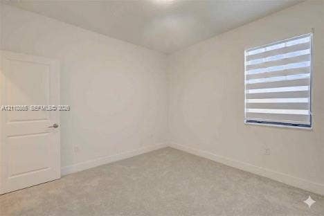 17552 SW 46th Street, Miramar, Miramar, FL 33029 Neutral interior space featuring carpeted flooring, a paneled interior door, and a horizontal banded roller shade