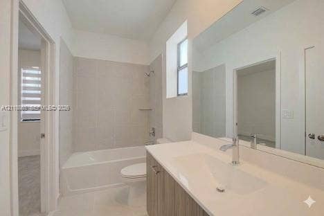 17552 SW 46th Street, Miramar, Miramar, FL 33029 Bathroom featuring a wood-finish vanity with a white integrated sink, full-width wall mirror, and a tub-shower combination with floor-to-ceiling tile surround