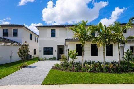 17552 SW 46th Street, Miramar, Miramar, FL 33029 Two-story exterior featuring light-toned smooth stucco finish, horizontal siding accents, dark-framed windows, paver driveway, and professional landscaping with palm trees