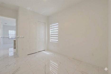 17552 SW 46th Street, Miramar, Miramar, FL 33029 Neutral-toned interior featuring large-format tile flooring with a veined pattern, two-panel interior doors, and a window fitted with horizontal dual-layer shades