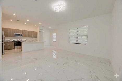 17552 SW 46th Street, Miramar, Miramar, FL 33029 Open-concept interior featuring large-format stone-finish tile flooring, horizontal-slat window shades, recessed lighting, and a modern kitchen with flat-panel cabinetry and a quartz-topped island