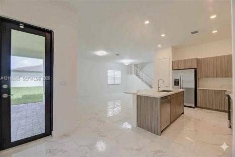 17552 SW 46th Street, Miramar, Miramar, FL 33029 Open-concept interior featuring light-toned stone-finish flooring, recessed lighting, and a kitchen equipped with wood-finish cabinetry, a quartz-topped center island, and stainless steel appliances