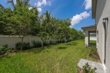 17552 SW 46th Street, Miramar, Miramar, FL 33029 Side yard featuring a grass lawn, paved stone walkway, perimeter masonry wall, and mature landscaping