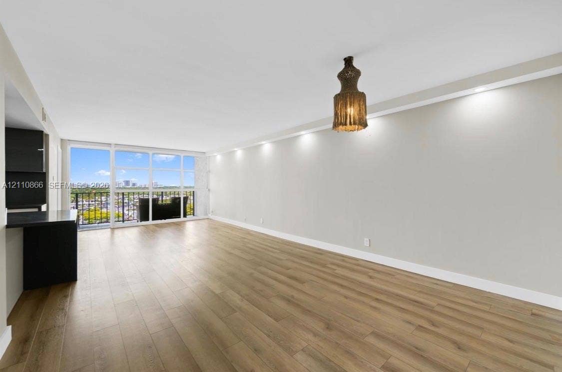 Living area featuring wood-finish flooring, floor-to-ceiling windows, recessed lighting, and a private balcony