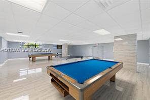 Expansive open-concept room featuring light-toned wood-finish flooring, recessed lighting, and a textured wall accent