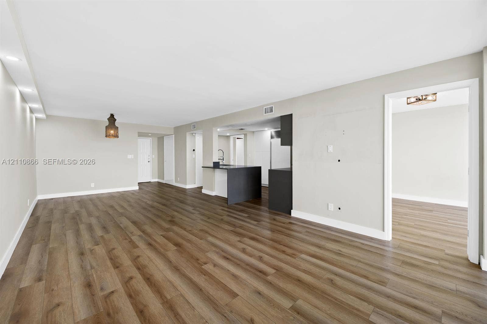 Open interior featuring wood-finish flooring, recessed lighting, and a kitchen peninsula with dark cabinetry