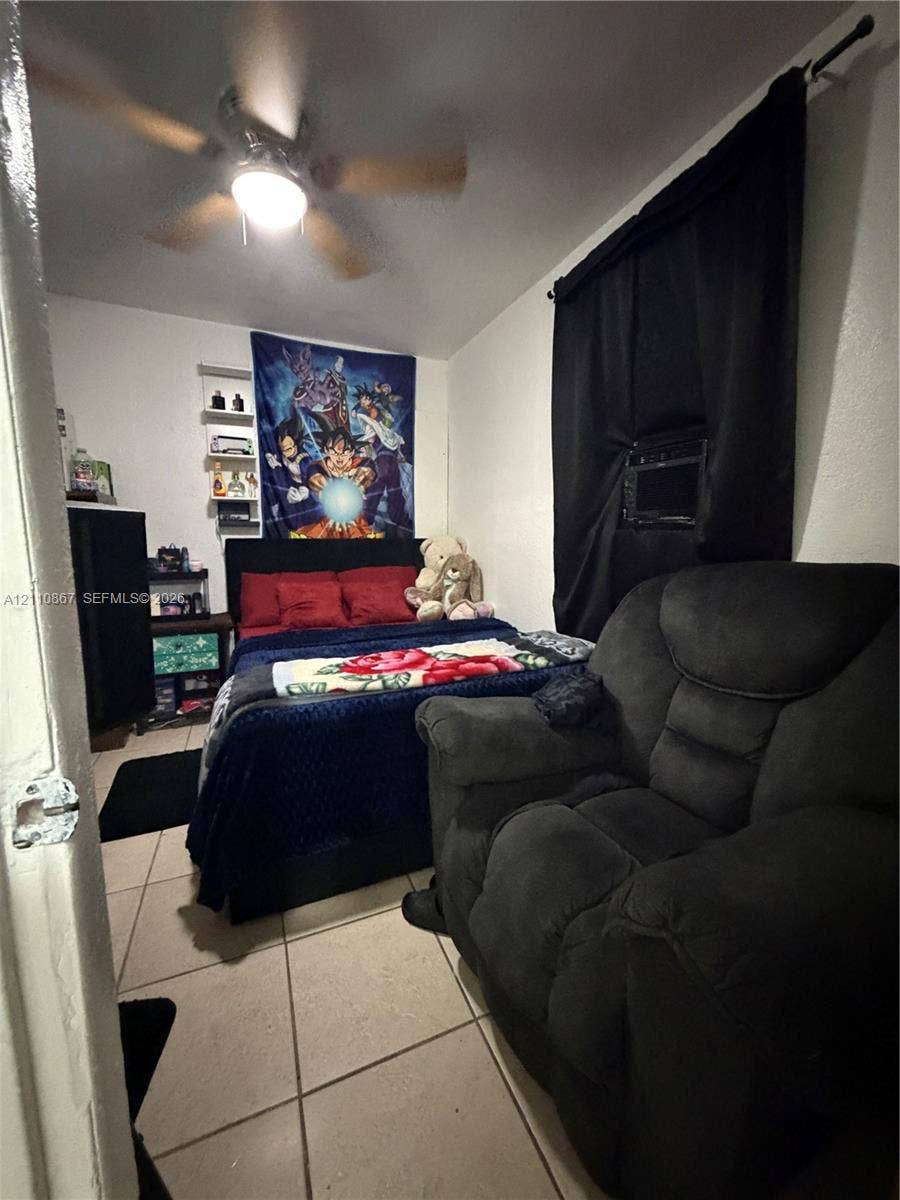 Room featuring tile flooring, ceiling fan with integrated lighting, and wall-mounted shelving