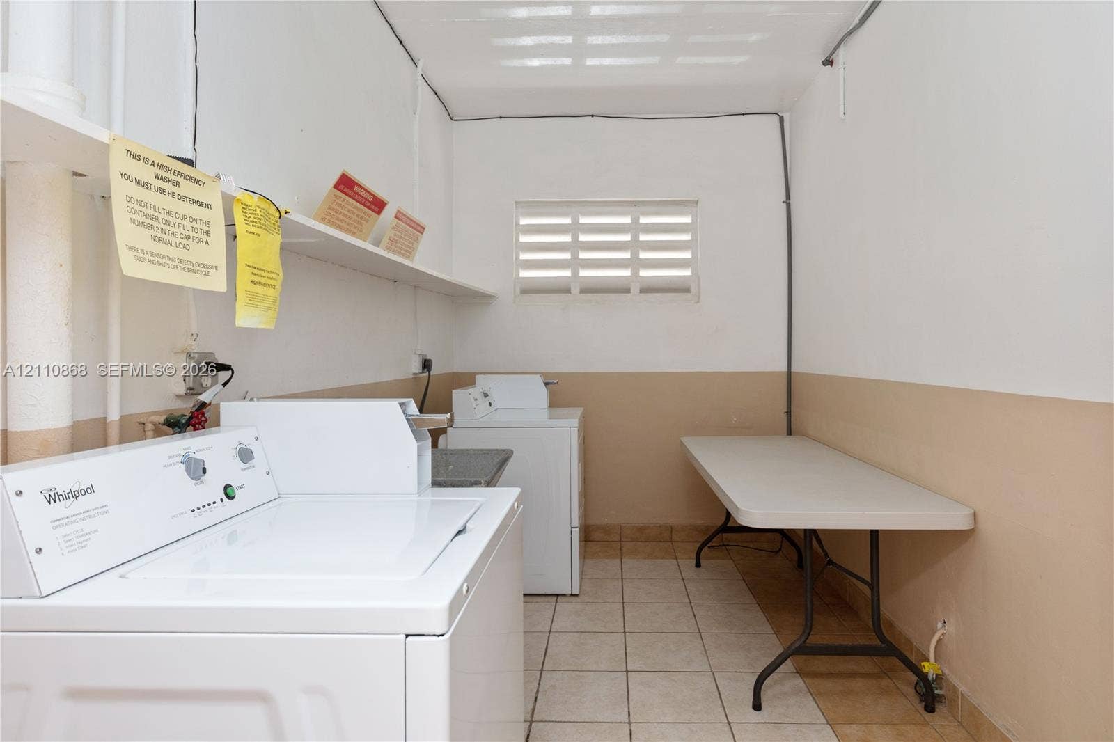 3121 S Ocean Drive, #209, Hallandale Beach, FL 33009 Laundry area featuring ceramic tile flooring, built-in shelving, and a louvered window