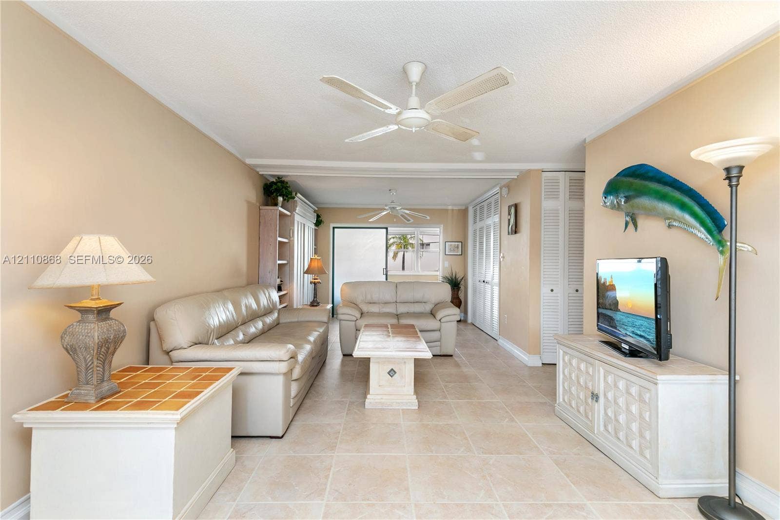 3121 S Ocean Drive, #209, Hallandale Beach, FL 33009 Neutral-toned interior space featuring oversized ceramic tile flooring, dual ceiling fans, built-in shelving, and louvered-style closet doors