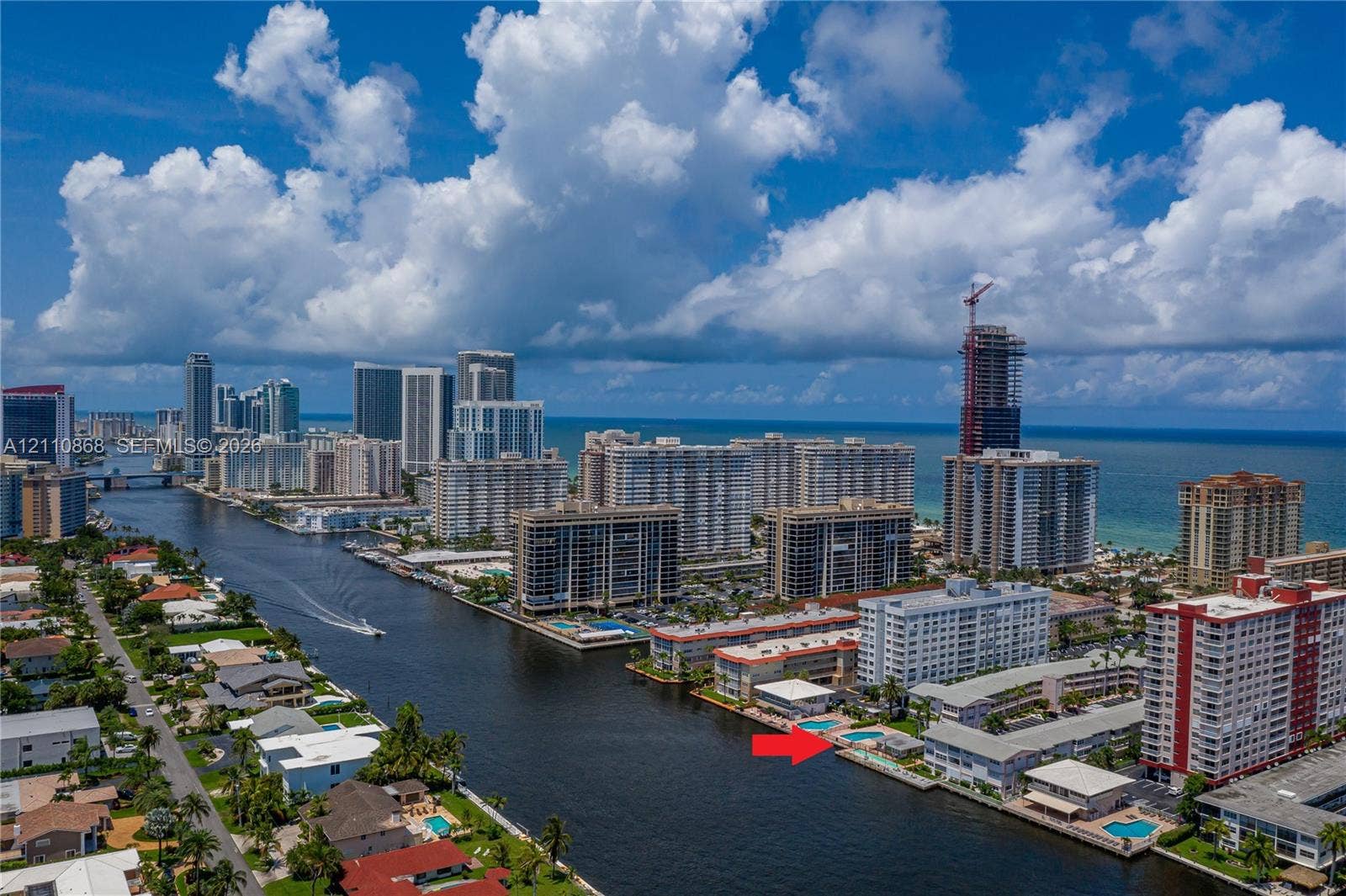 3121 S Ocean Drive, #209, Hallandale Beach, FL 33009 Waterfront complex featuring a swimming pool, canal access, and urban skyline backdrop