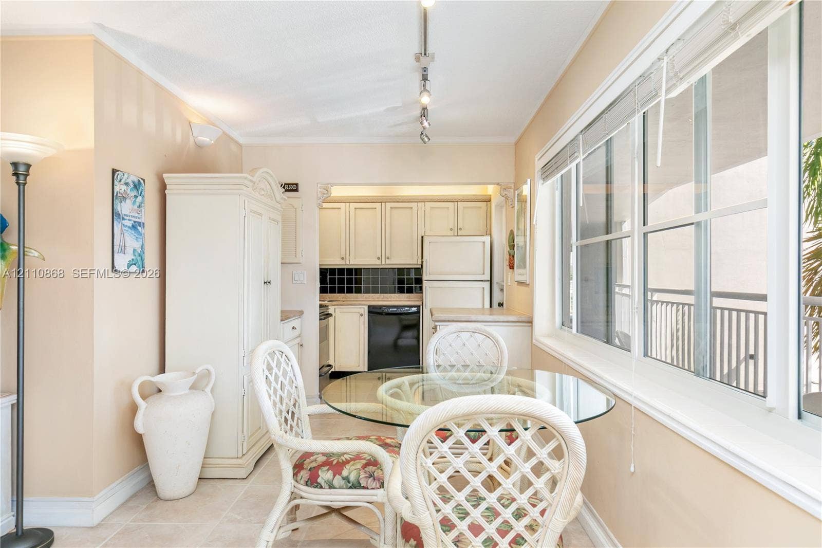 3121 S Ocean Drive, #209, Hallandale Beach, FL 33009 Kitchen featuring white shaker-style cabinetry, a contrasting dark tile backsplash, and built-in white cabinetry, complemented by tile flooring and a multi-pane sliding glass window