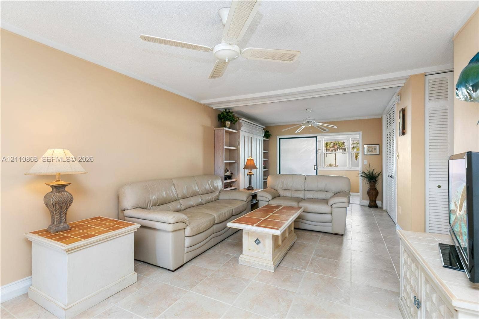 3121 S Ocean Drive, #209, Hallandale Beach, FL 33009 Neutral-toned tile flooring, dual ceiling fans, built-in shelving unit, and louvered closet doors