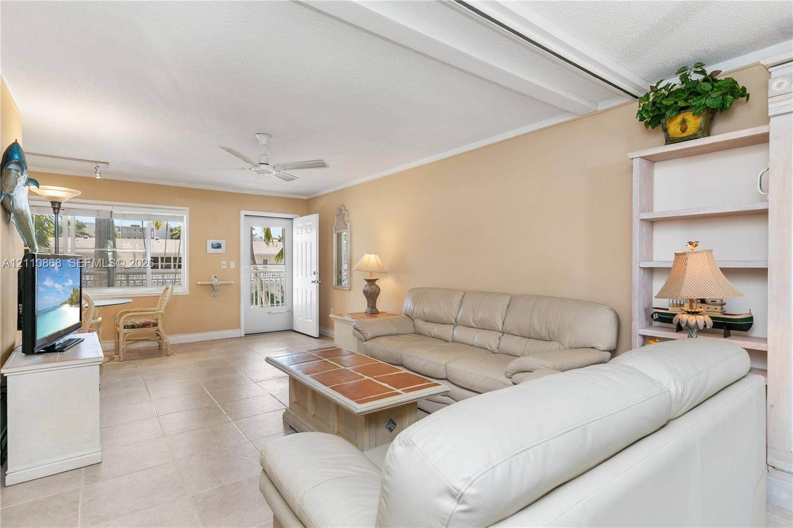 3121 S Ocean Drive, #209, Hallandale Beach, FL 33009 Neutral tile flooring, built-in shelving unit, ceiling fan, and large windows providing natural light