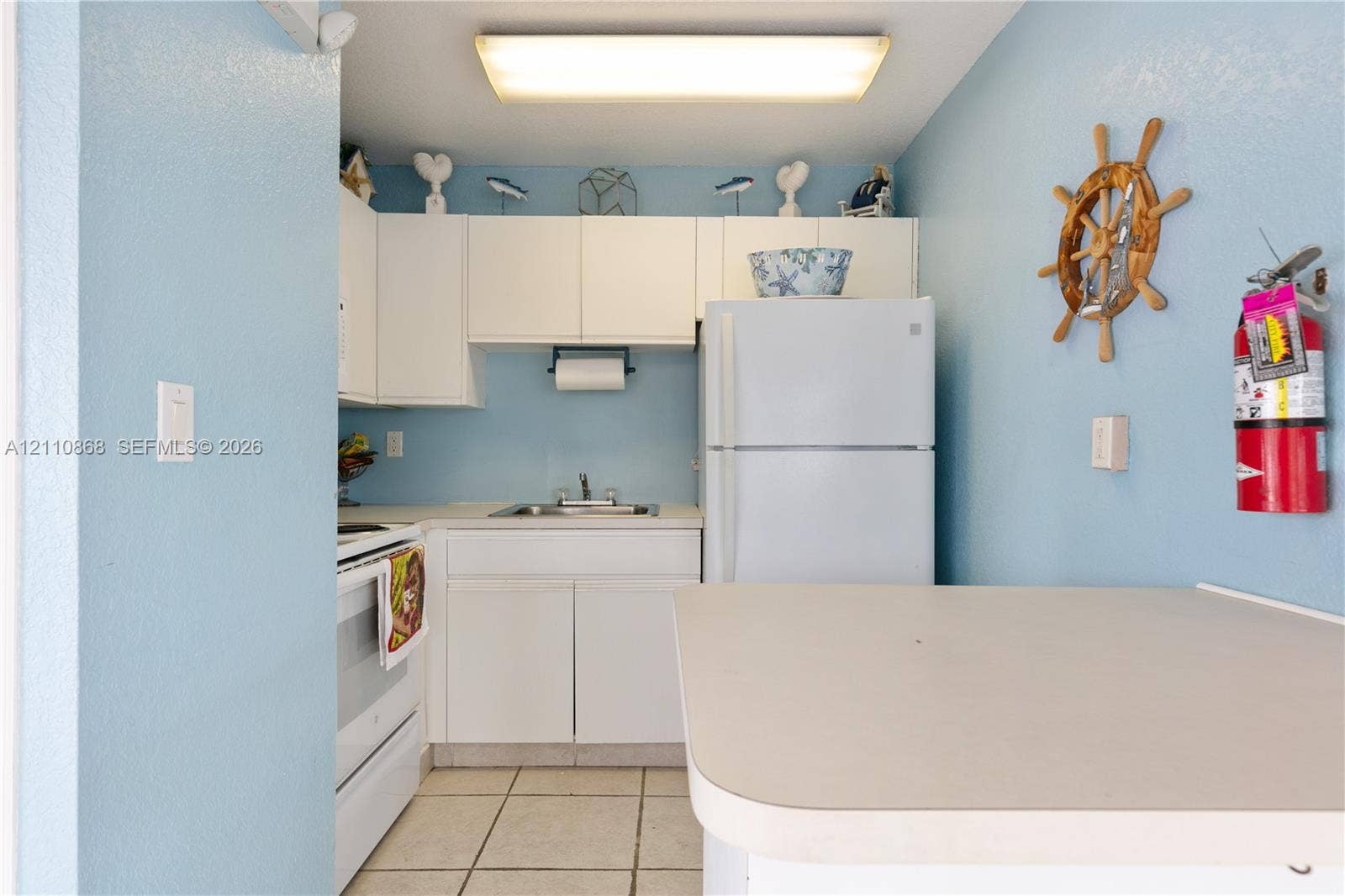 3121 S Ocean Drive, #209, Hallandale Beach, FL 33009 Club house, Kitchen featuring white cabinetry, integrated refrigerator, white range, rectangular basin sink with dual-handle faucet, and tile flooring