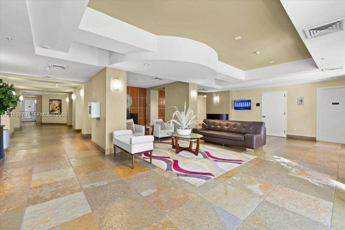 1755 E Hallandale Beach Boulevard, #MEZ5E, Hallandale Beach, FL 33009 Large-scale interior featuring multi-toned stone tile flooring, an intricate coffered ceiling with recessed lighting, and wall-mounted sconces