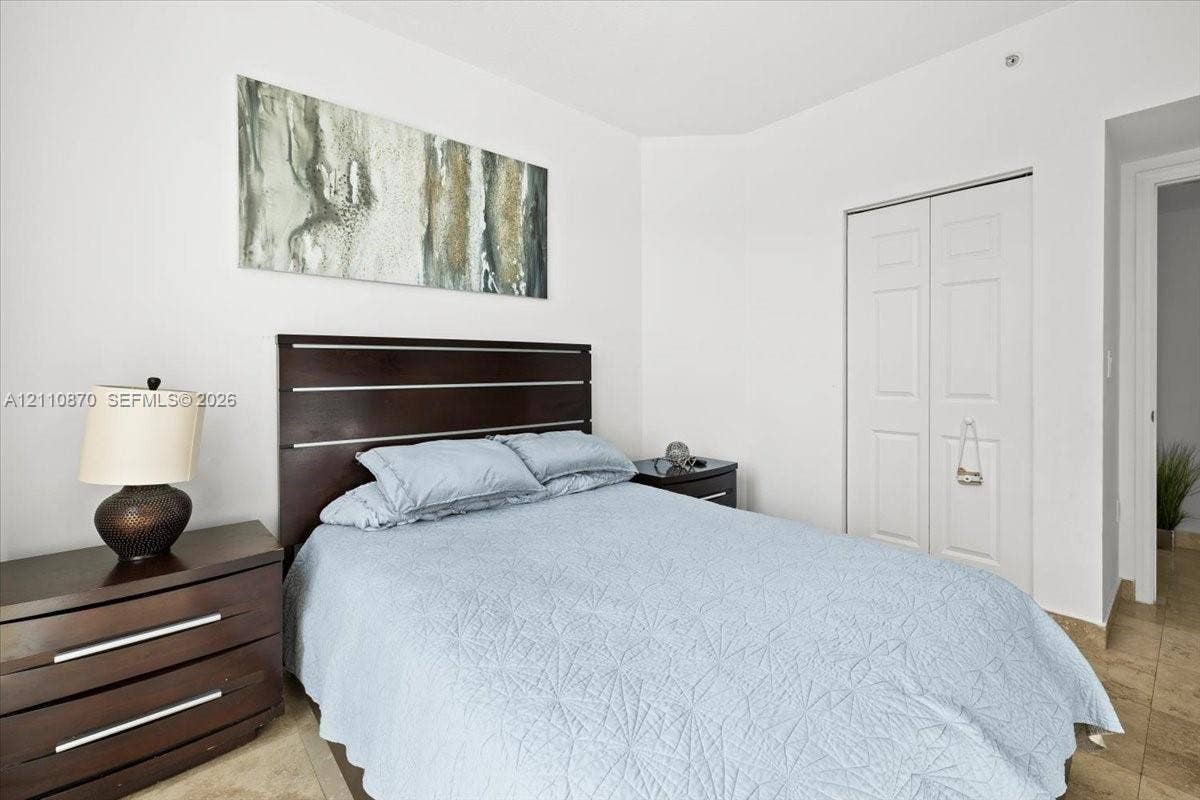 1755 E Hallandale Beach Boulevard, #MEZ5E, Hallandale Beach, FL 33009 Neutral-toned interior space featuring light-colored stone-finish flooring and a double-door closet with recessed panel detailing