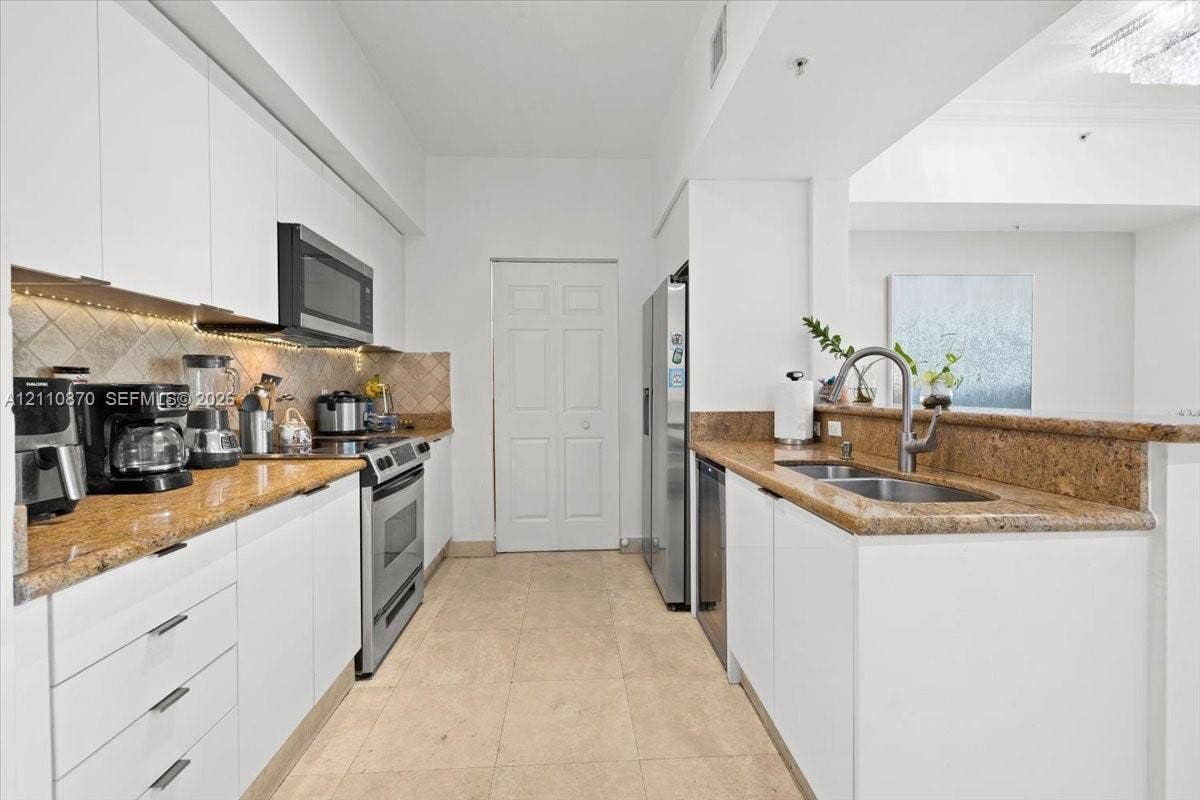 1755 E Hallandale Beach Boulevard, #MEZ5E, Hallandale Beach, FL 33009 Kitchen featuring white cabinetry, stone countertops, tiled backsplash, stainless steel appliances, and tile flooring
