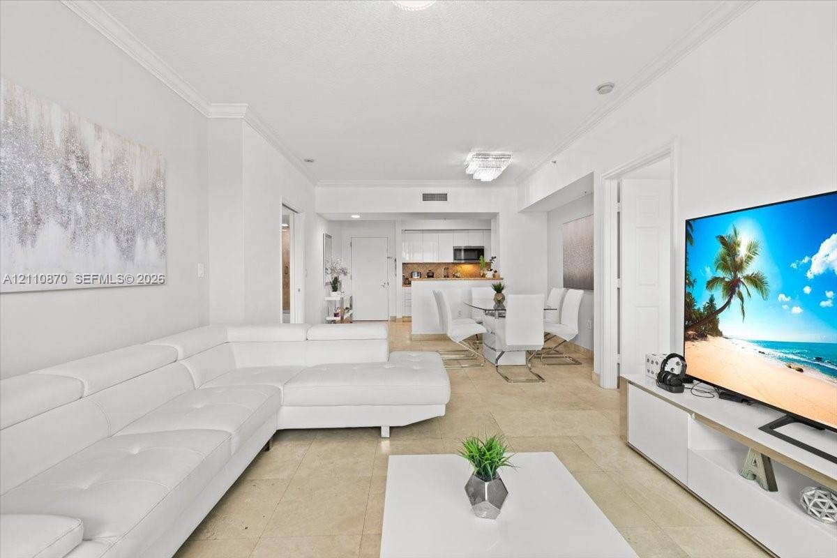 1755 E Hallandale Beach Boulevard, #MEZ5E, Hallandale Beach, FL 33009 Living area featuring crown molding, neutral tile flooring, and floor-to-ceiling glass sliding doors opening to a private balcony