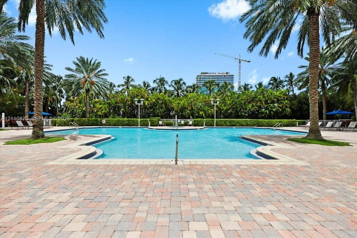 1755 E Hallandale Beach Boulevard, #MEZ5E, Hallandale Beach, FL 33009 Custom-shaped swimming pool with a stone paver deck, perimeter landscaping, and mature palm trees