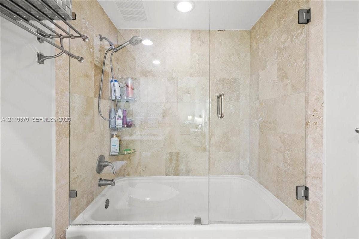 1755 E Hallandale Beach Boulevard, #MEZ5E, Hallandale Beach, FL 33009 Bathtub with a glass enclosure, wall-mounted shower head, recessed lighting, and tiled wall surround
