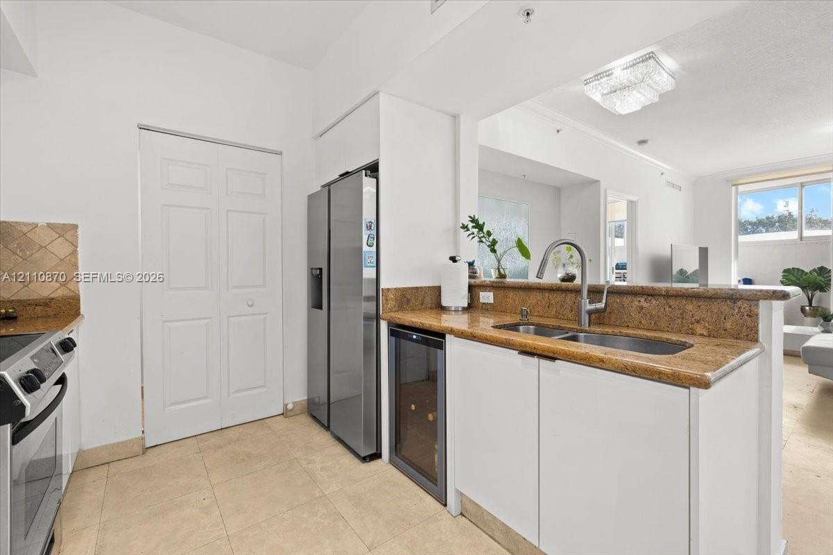 1755 E Hallandale Beach Boulevard, #MEZ5E, Hallandale Beach, FL 33009 Kitchen featuring stone countertops, integrated under-counter wine storage, stainless steel refrigerator, tile flooring, and double-basin undermount sink with gooseneck faucet