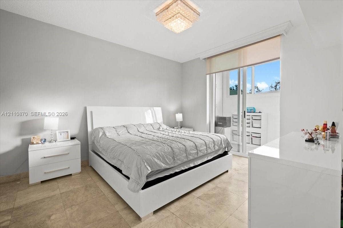 1755 E Hallandale Beach Boulevard, #MEZ5E, Hallandale Beach, FL 33009 Neutral-toned space featuring large-format tile flooring, a geometric crystal ceiling fixture, and a sliding glass door providing external access