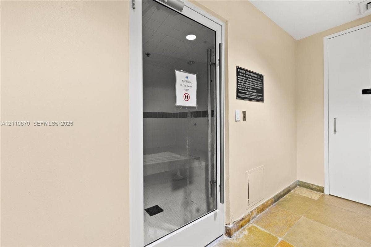1755 E Hallandale Beach Boulevard, #MEZ5E, Hallandale Beach, FL 33009 Steam room featuring a glass-panel door, built-in bench seating, recessed lighting, and stone flooring