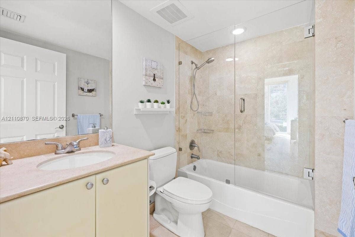 1755 E Hallandale Beach Boulevard, #MEZ5E, Hallandale Beach, FL 33009 Full-height vanity cabinet with a stone countertop, recessed oval sink, stone-tiled shower surround, and a frameless glass tub enclosure