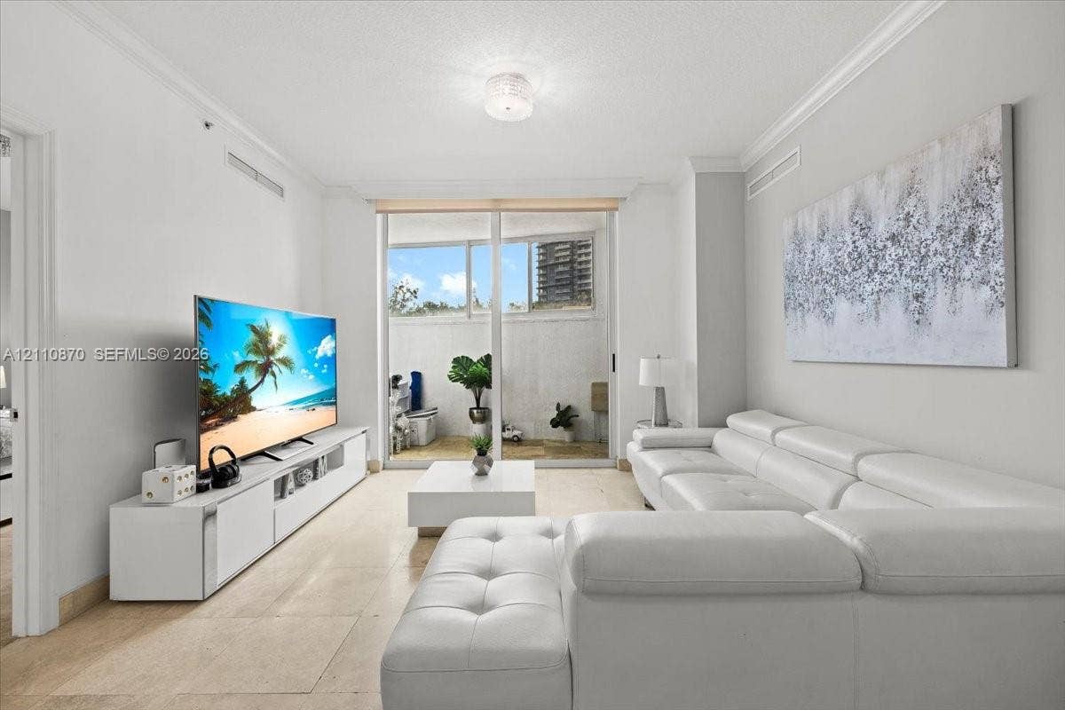 1755 E Hallandale Beach Boulevard, #MEZ5E, Hallandale Beach, FL 33009 Open-concept interior featuring light-toned tile flooring, crown molding, a kitchen breakfast bar, and recessed lighting
