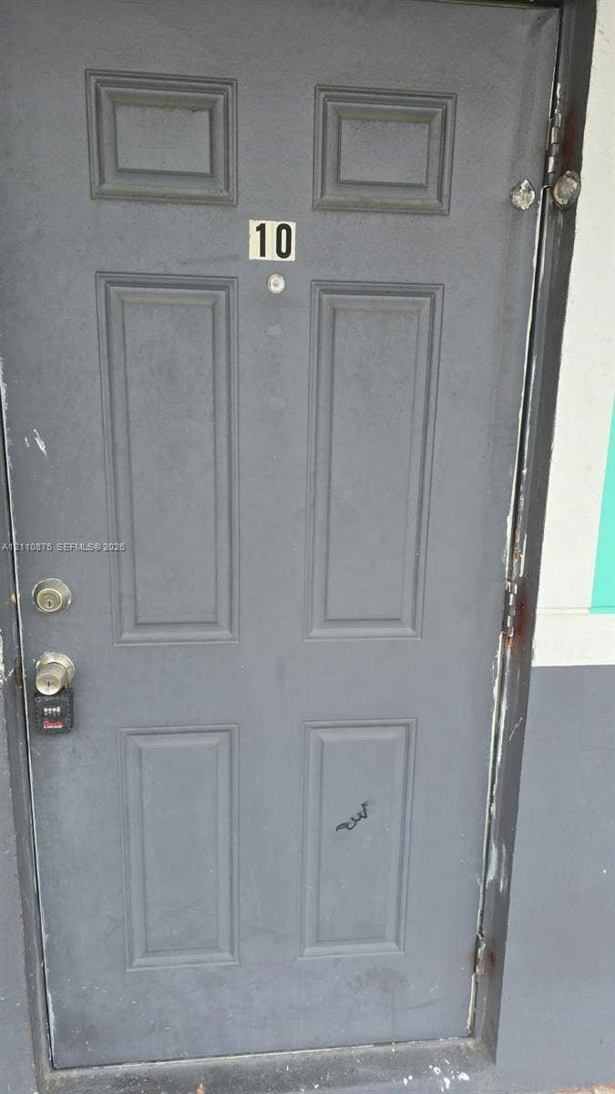 535 NW 7th Street, #10, Miami, Miami, FL 33136 Gray six-panel entry door with integrated peephole, numerical signage, and metallic hardware