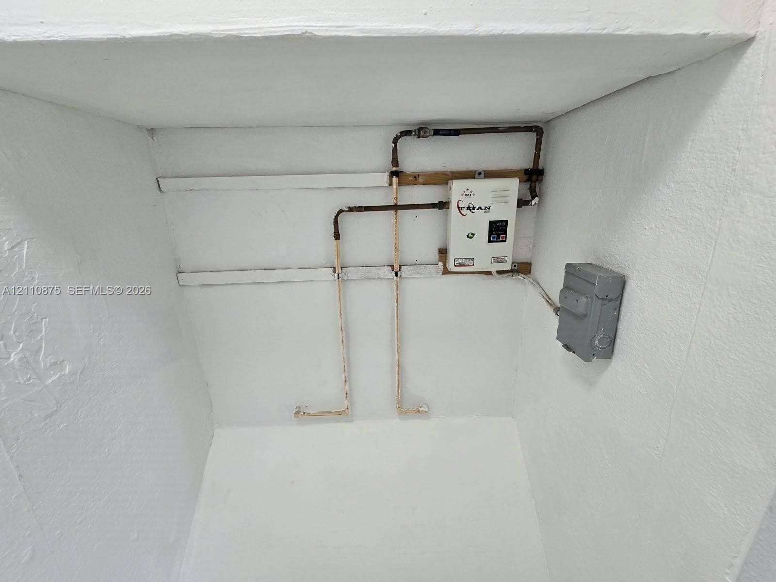 535 NW 7th Street, #10, Miami, Miami, FL 33136 Tankless electric water heater featuring copper plumbing connections and a wall-mounted electrical disconnect switch