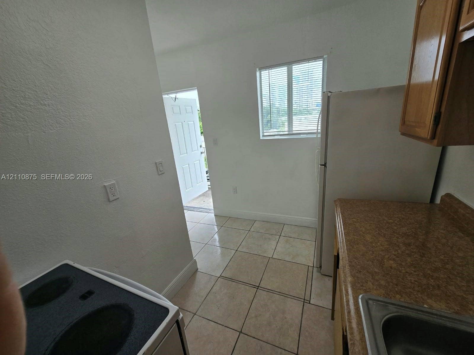 535 NW 7th Street, #10, Miami, Miami, FL 33136 Kitchen featuring tile flooring, wood-finish cabinetry, a white refrigerator, an electric range, and a single-pane window