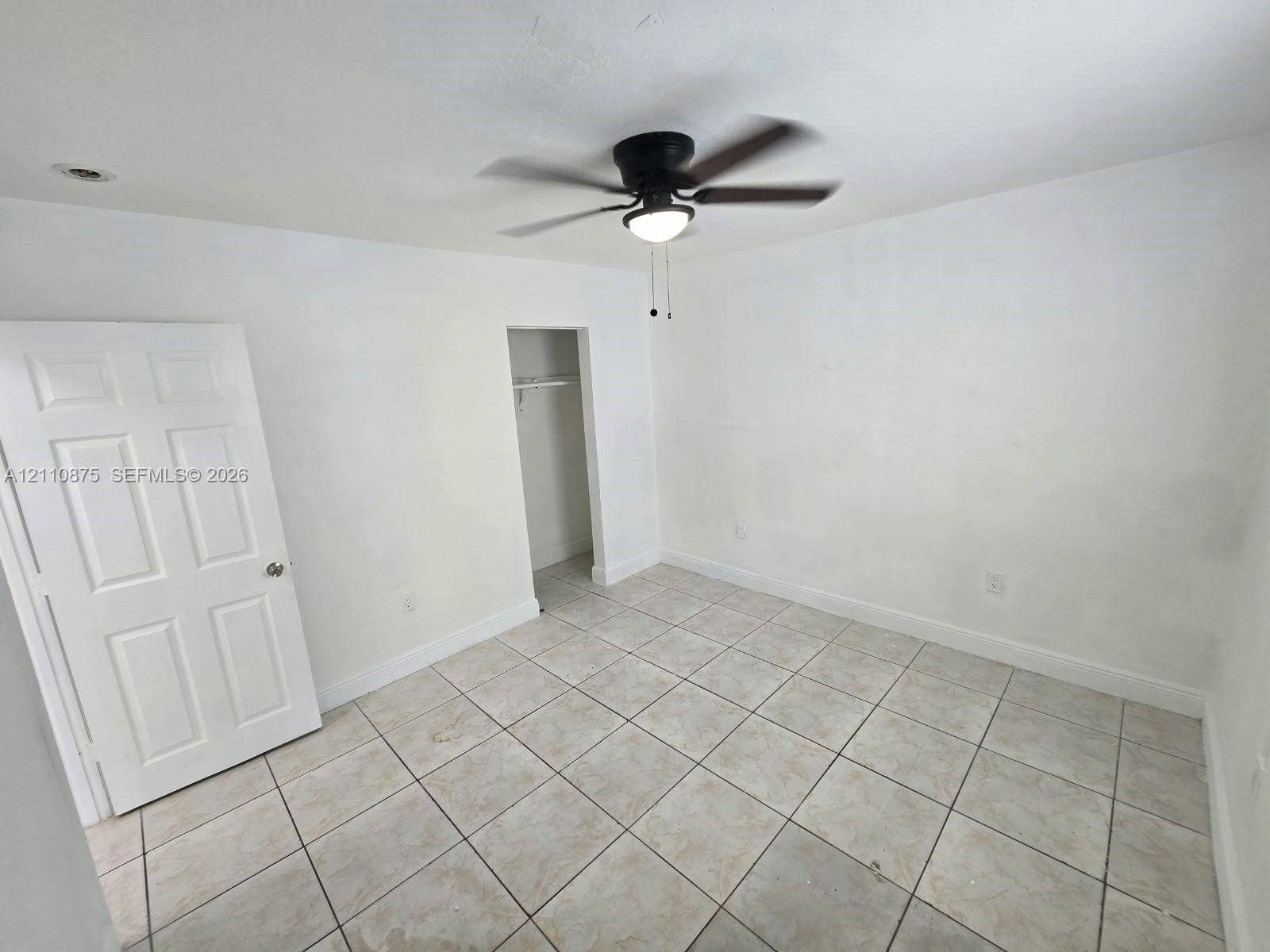 535 NW 7th Street, #10, Miami, Miami, FL 33136 Interior space featuring light-colored tile flooring, a six-panel door, a walk-in closet, and a ceiling fan with integrated lighting